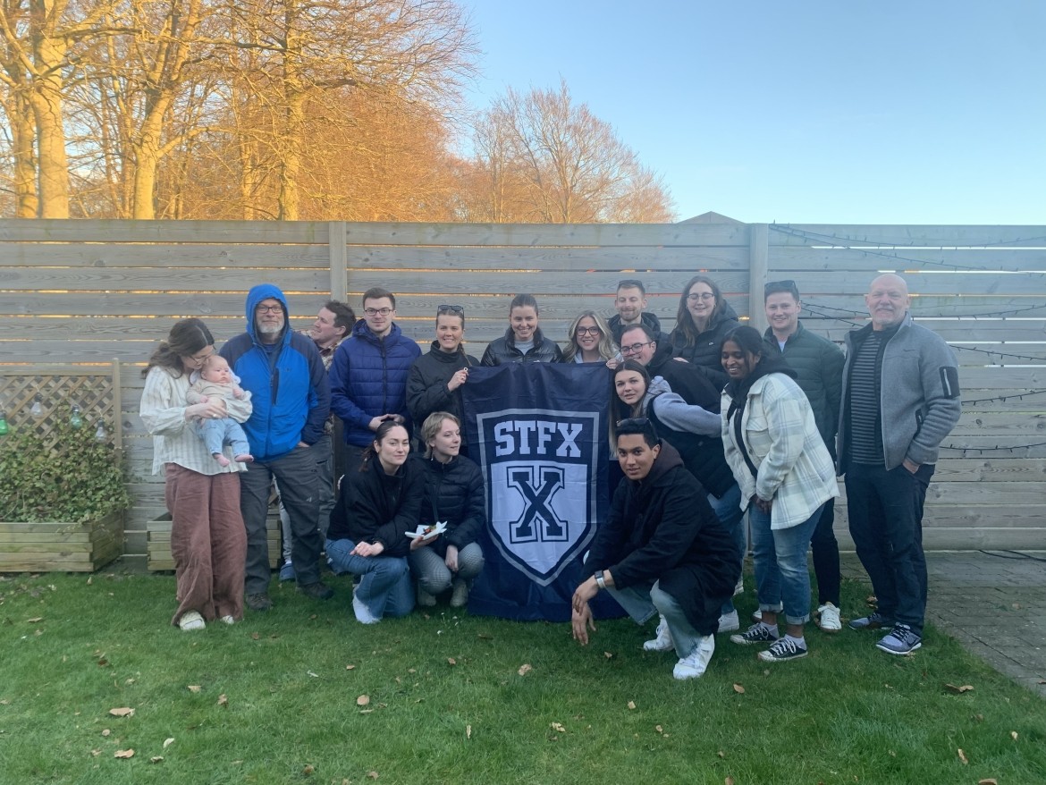 A group of people posing for a picture in front of a fence