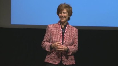 Leahy standing in front of a screen while wearing a pink blazer